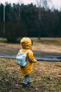 Small child walking outdoors with a little backpack