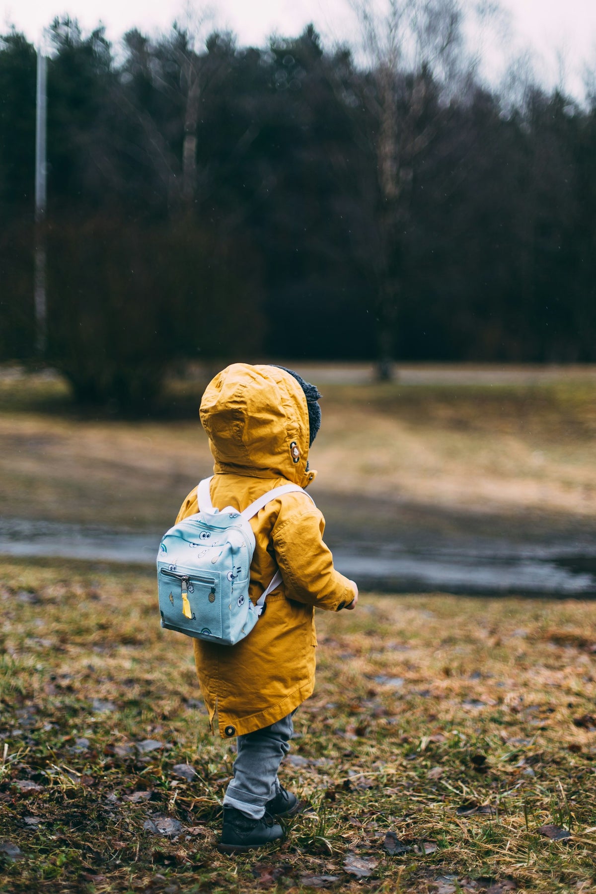 Small child walking outdoors with a little backpack