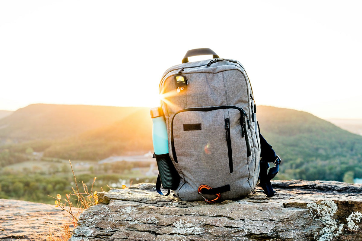 Hiking pack and a bottle on rock at sunset