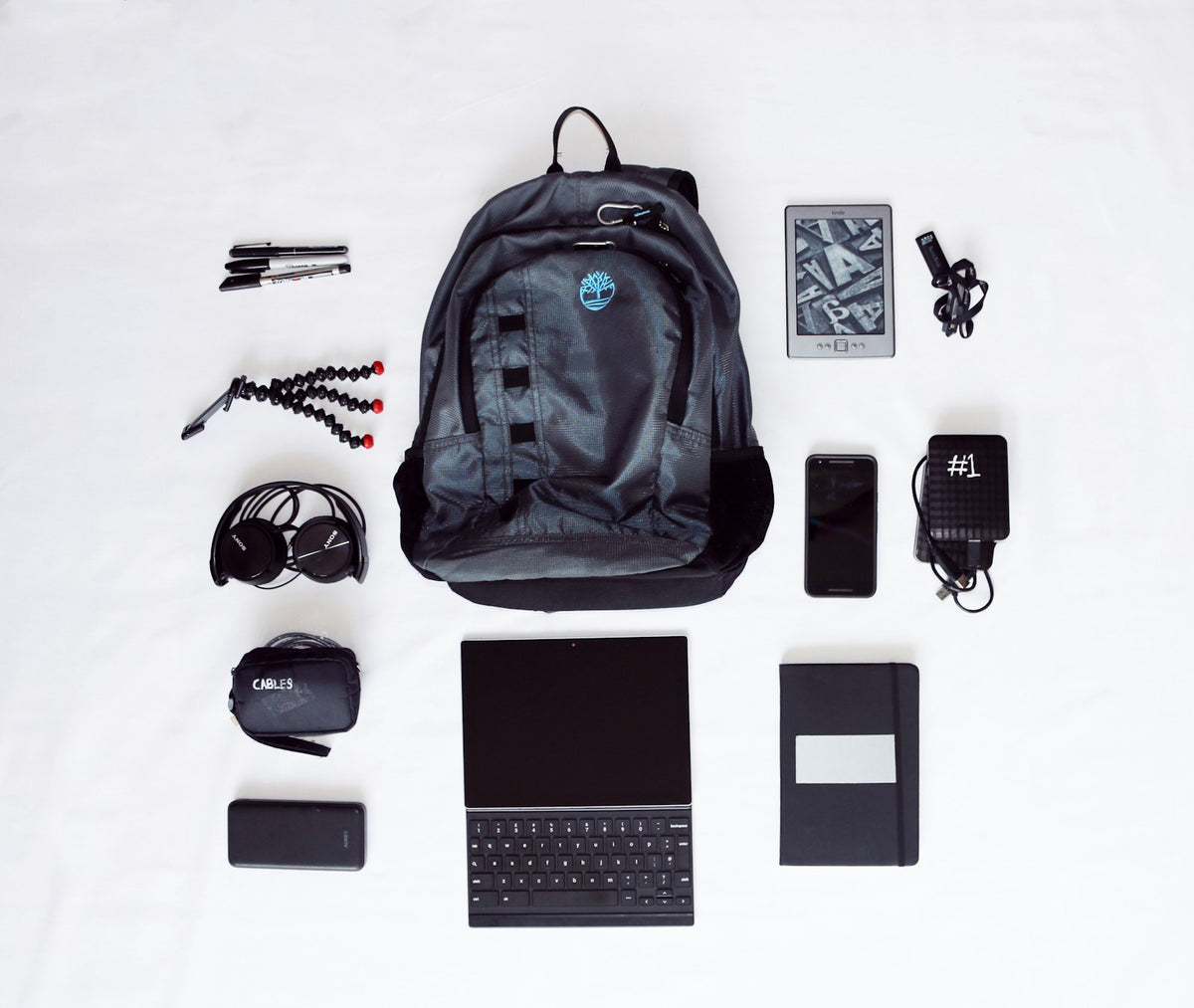 Backpack laid out with a laptop, headphones and a phone