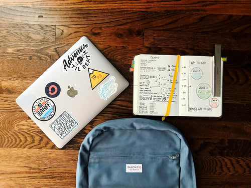 Blue backpack laid out beside a book and a laptop