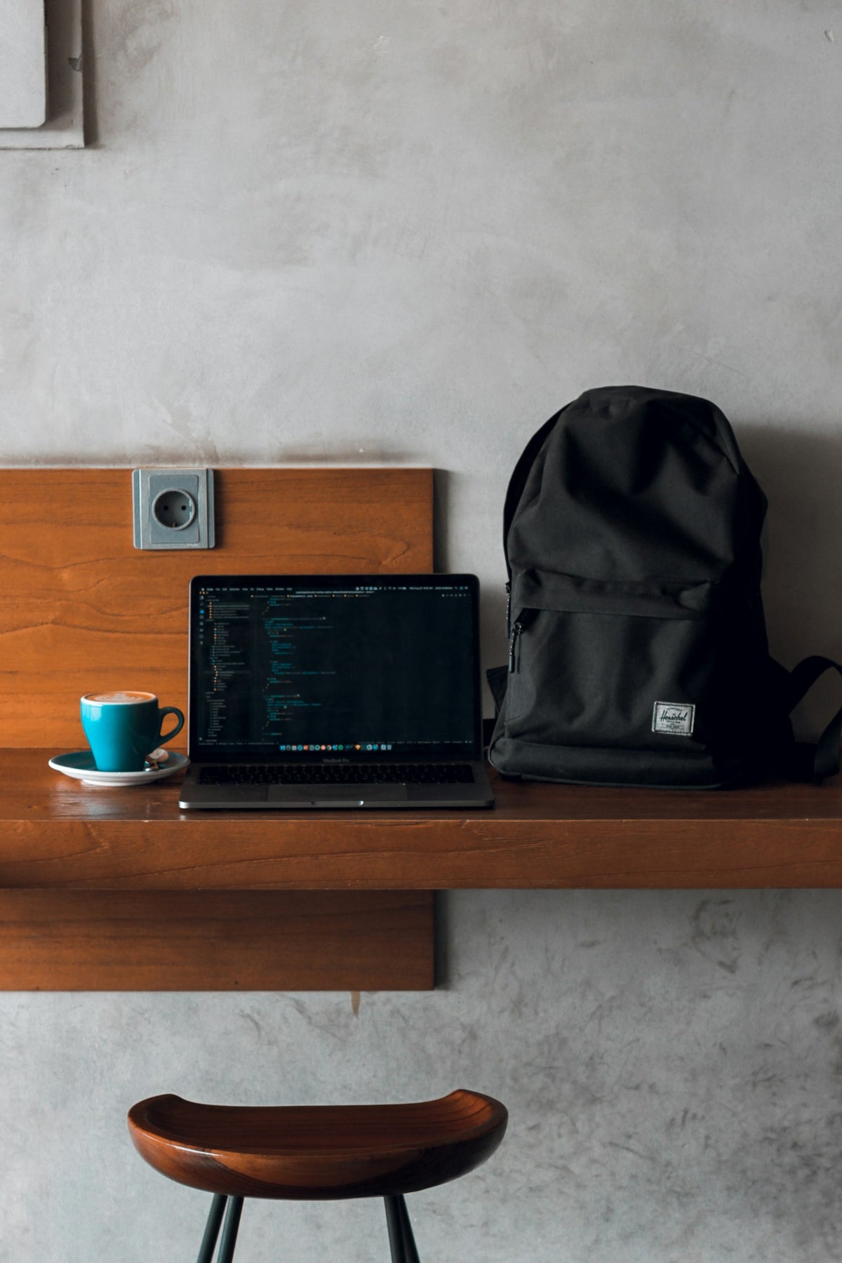 Backpack on a desk beside a laptop and a mug