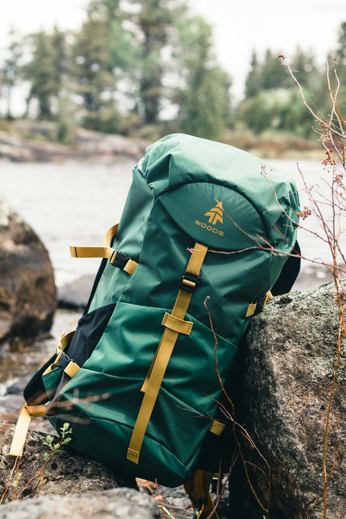Green and brown backpack resting on rock