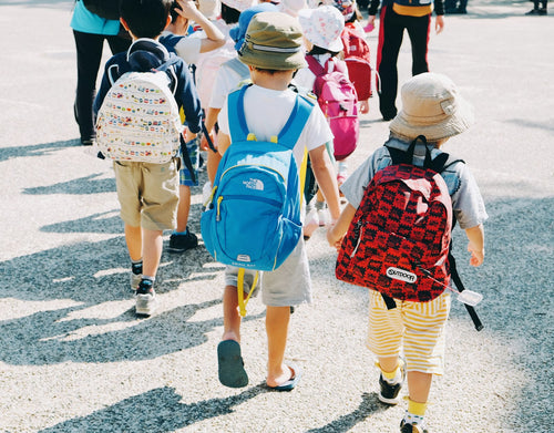 People walking along a grey road carrying packs