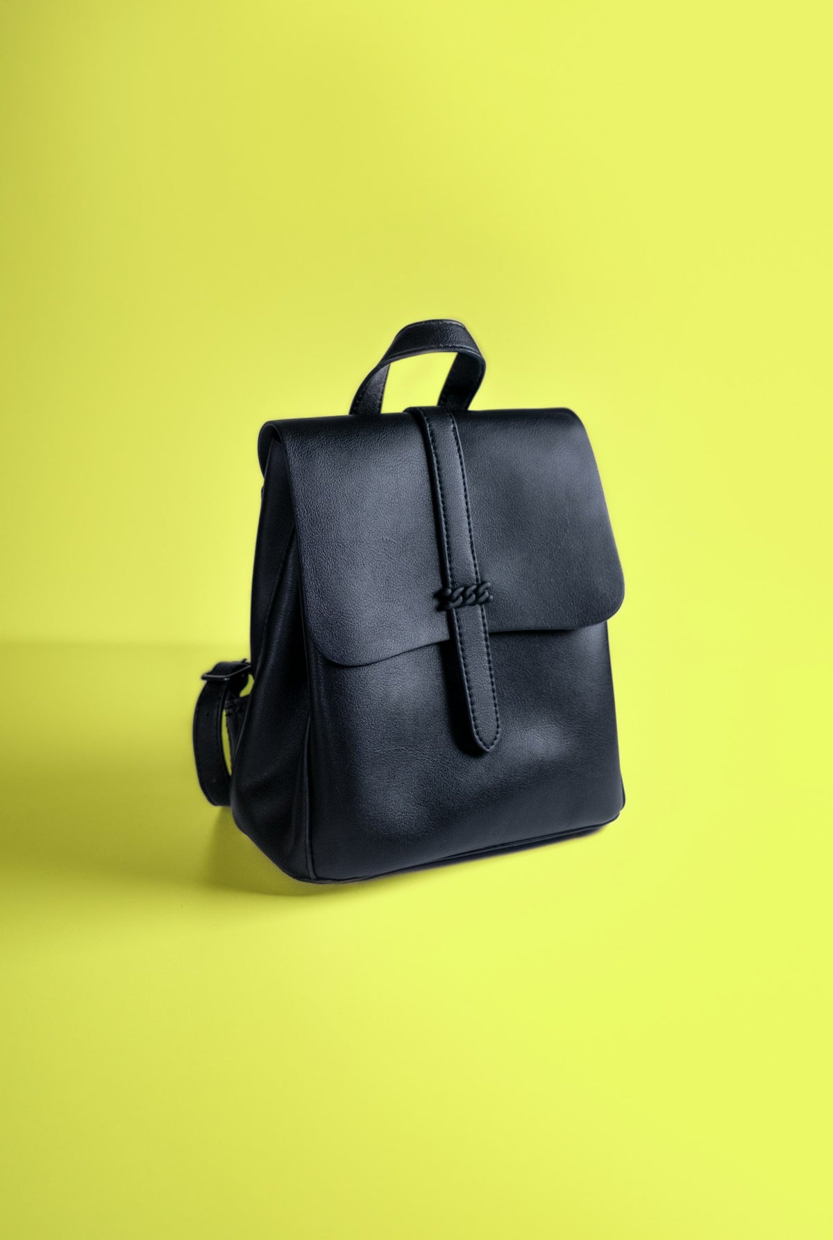 Black leather backpack on a plain backdrop
